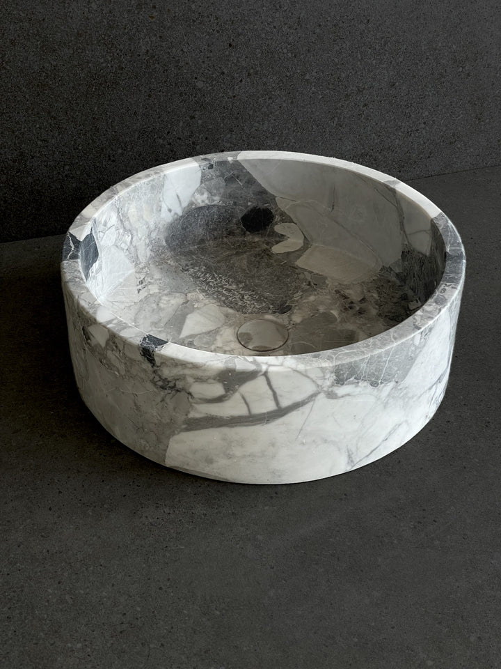 Round marble-look ceramic basin with smooth polished finish on dark surface