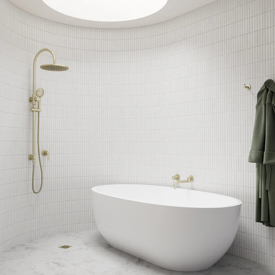 Freestanding white bathtub with gold shower system and wall-mounted shower head in modern tiled bathroom