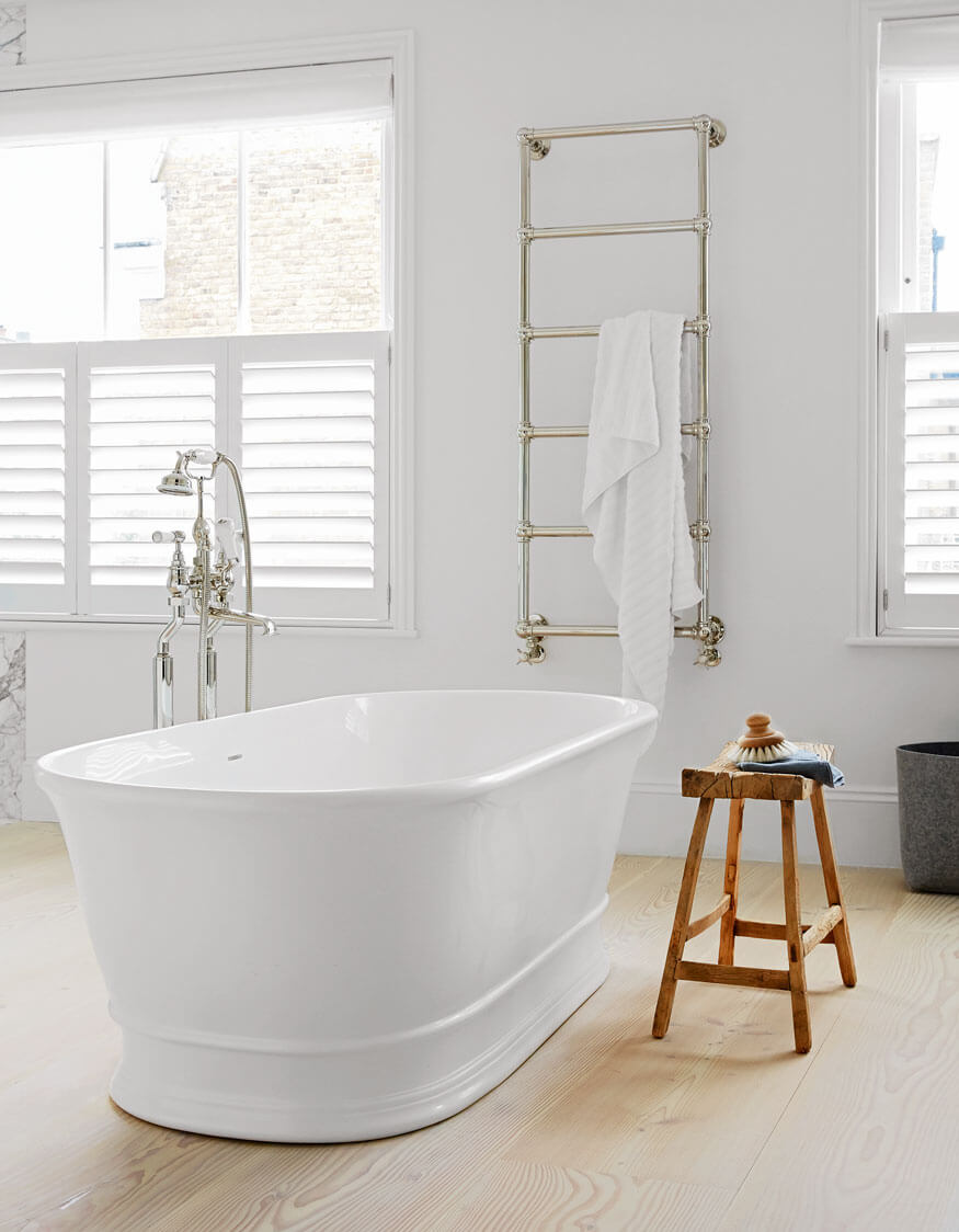 Modern bathroom with a freestanding bathtub, towel rack, and wooden stool.