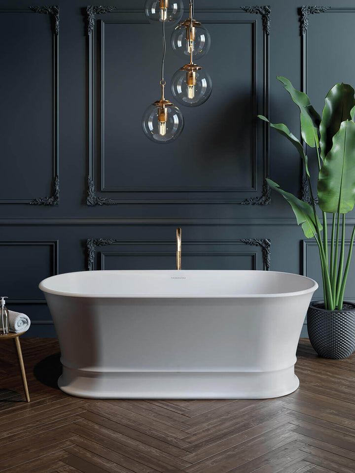 White freestanding bathtub in a stylish bathroom with dark walls, pendant lights, and a plant.